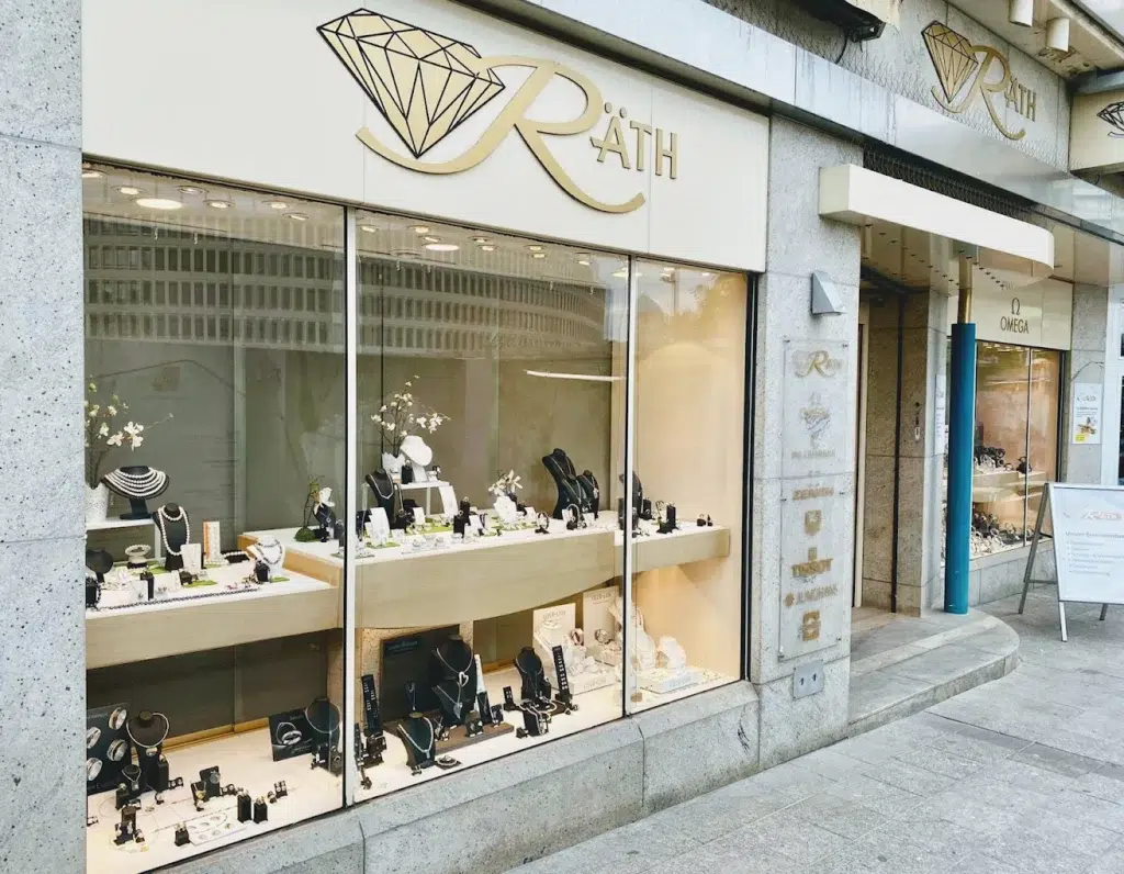 Ein elegantes Juweliergeschäft mit Schmuck in beleuchteten Auslagen und einem goldenen Schild.