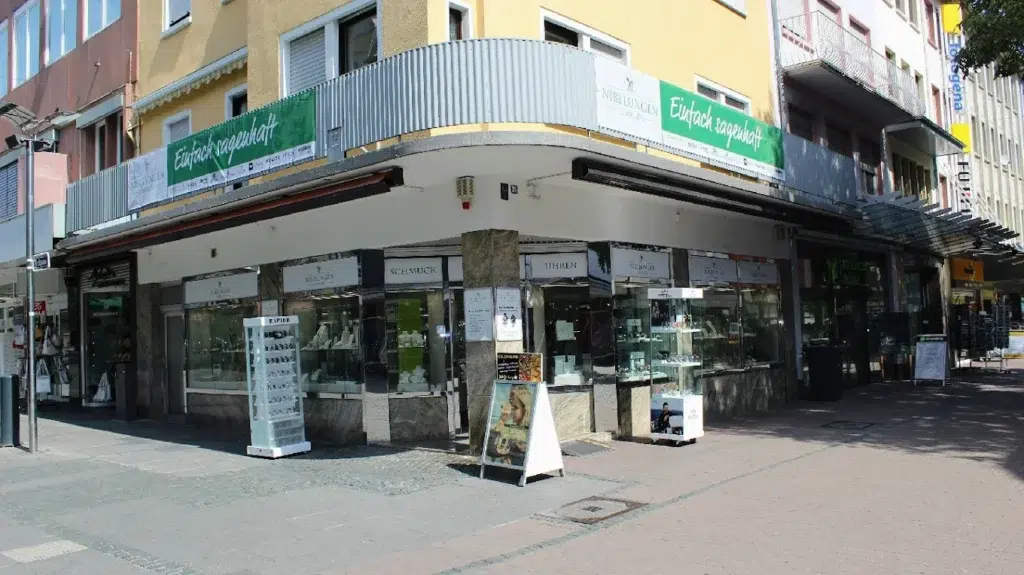 Geschäftsecke mit gelbem Gebäude, Schaufenstern und grünen Markisen.